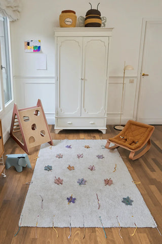 Bloemenvloerkleed met losse bloemen in een kinderkamer.