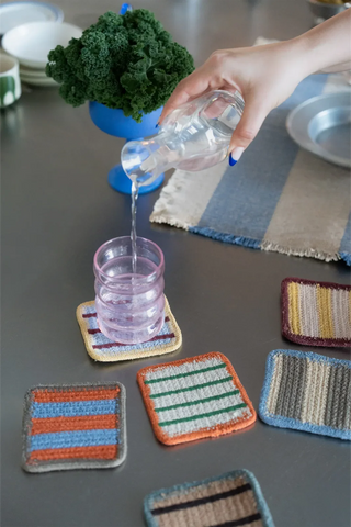 Gestreepte onderzetters met een glas op tafel.