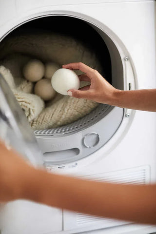 Drogerballen worden bij een vloerkleed in de droger gelegd