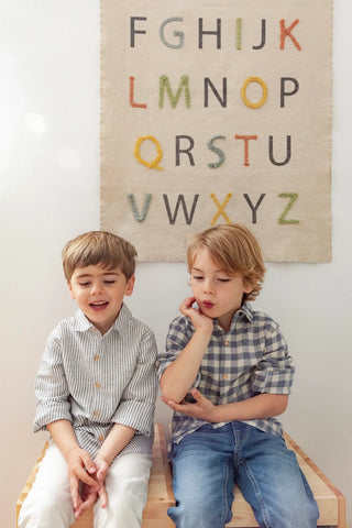 Wanddecoratie met gekleurde alfabetletters achter twee kinderen.