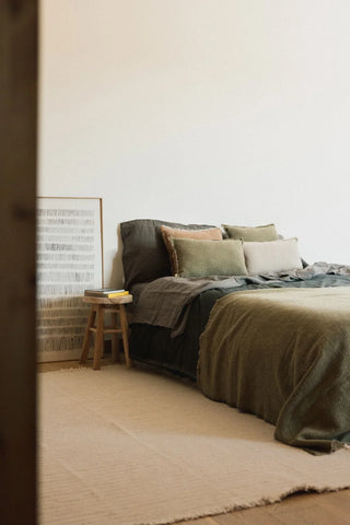 Handloom-plaid in kaki over een bed.