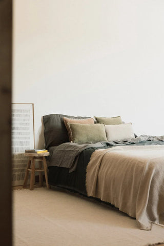Handloom-plaid in naturel en beige over een bed in een slaapkamer.
