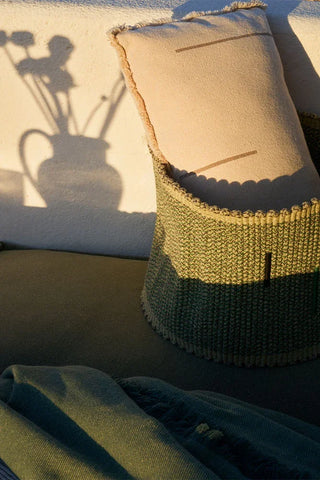 Groene Vertical-opbergmand met een kussen in zonlicht naast een plaid.