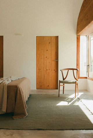 Lorena Canals Handloom Kaki vloerkleed naast een bed