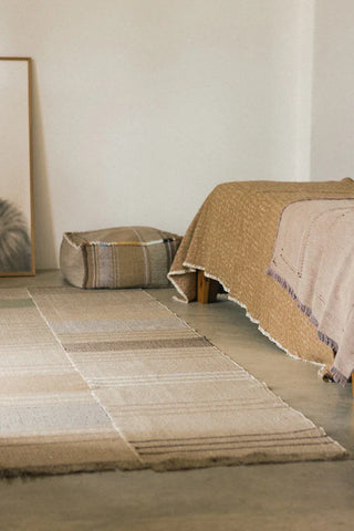 Oaxaca-vloerkleed met strepen naast een bed.