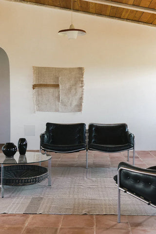 Pedregal-wandhanger boven zwarte stoelen.