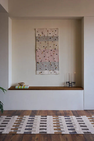 Naturelkleurige Intersecting-loper met grijze, bruine en okerkleurige blokken langs een wandnis.