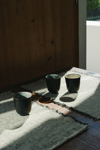 Handloom-placemat in naturel met donkergrijze rand met servies op een tafel.