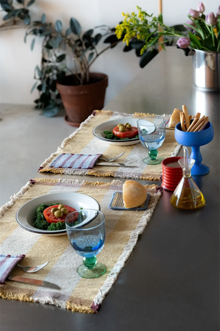 Gele placemats met bestekvak op een gedekte tafel.