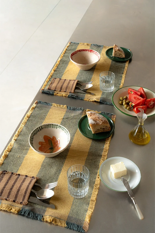 Geel-blauwgroene placemats op een gedekte tafel.
