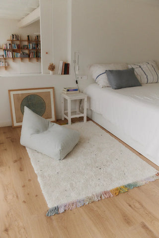 Blauwgroene Cleo-zitzak op een vloerkleed naast een bed.