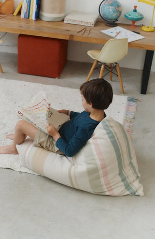 Kind leest op een Cleo-zitzak met gekleurde strepen.