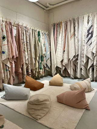 Lorena Canals Cleo Vintage Nude poef rechts vooraan in een showroom met andere poefs