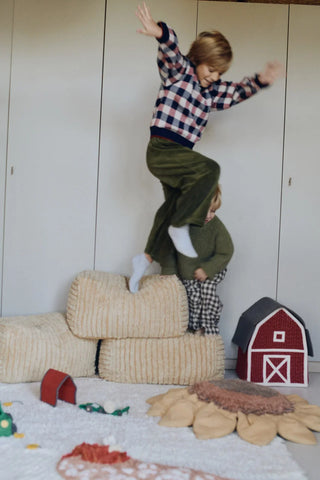 Kind speelt op meerdere Haystack-poefs in een kamer.