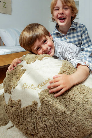 Kinderen bij een naturel wereldkaartpoef.