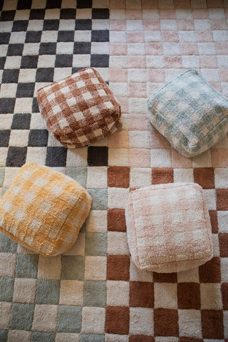 Roze Vichy-poef rechts onder tussen andere gekleurde poefs en vloerkleden.