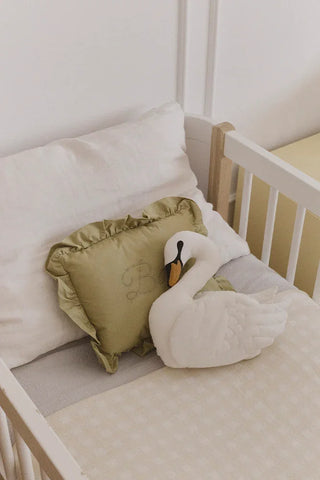 Groen Baby-kussen achter een zwaankussen in een kinderbed.
