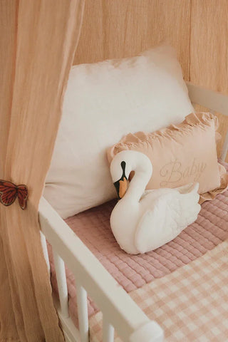 Roze Baby-kussen achter een zwaankussen in een kinderbed.