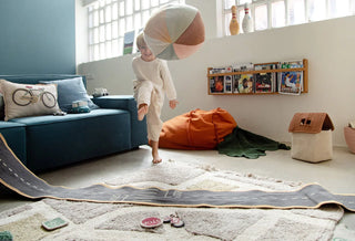 Kind speelt met het ronde Ball-kussen in een kamer.
