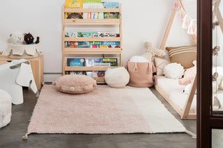 Roze rond vloerkussen in een kinderkamer.