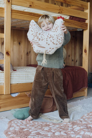 Kind houdt een kippenvormig kussen vast.