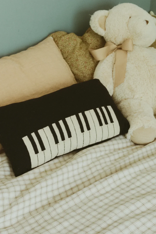 Pianokussen op een bed naast een knuffel.