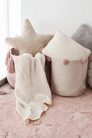 Beige sterkussen bij een mand met kussens.