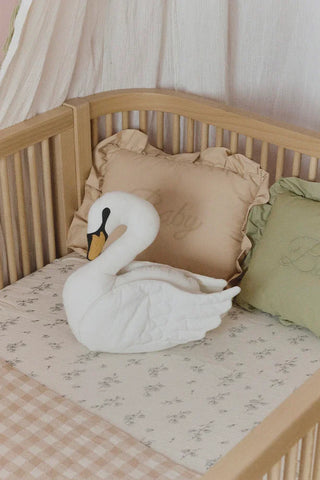 Zwaankussen in een kinderbed tussen andere kussens.