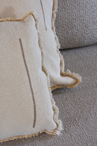 Detail van naturelkleurige Vertical-kussens met franjes op een bank.