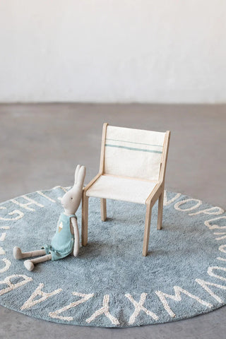 Lichte Vintage Blue-stoelhoes met blauwgrijze lijnen op een houten kinderstoel op een alfabetkleed.