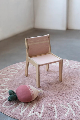 Oudroze Vintage Nude-stoelhoes op een houten kinderstoel op een roze alfabetkleed.