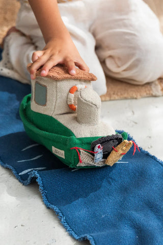 Kind speelt met een boot op de zeemat.