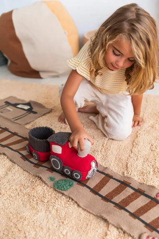 Kind speelt met trein op een uitgerolde spoorwegmat.