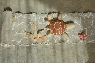 Uitgerolde zeespeelmat met schildpadfiguur.