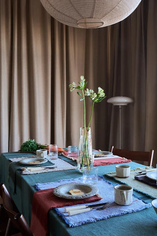 Vertical-tafelkleed in groen op een gedekte eettafel.