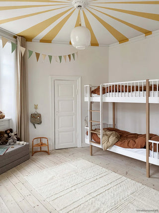 Licht Ari Sheep White-vloerkleed in een kinderkamer met stapelbed en gestreept plafond.