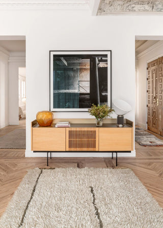 Licht Autumn Breeze-vloerkleed met donkere lijnen voor een houten dressoir.