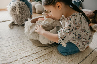 Kind speelt met de Pink Nose Sheep-mand op een kleed.