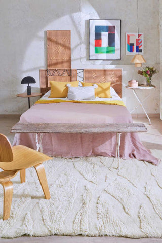 Enkang Ivory vloerkleed bij een bed met roze beddengoed