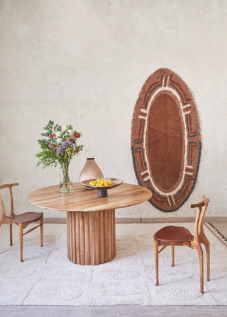 Karibu-vloerkleed aan een muur bij een ronde eettafel.