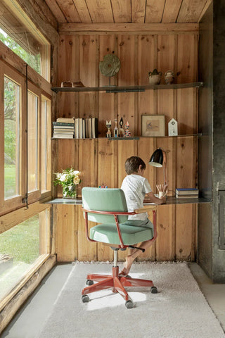 Licht Koa Sandstone-vloerkleed onder een bureaustoel in een houten werkkamer.