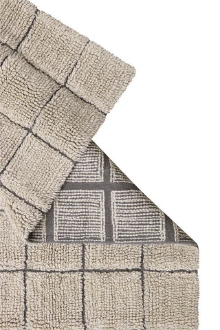 Omgeslagen hoek van zandkleurig Mosaic-vloerkleed met zichtbare geweven onderzijde.