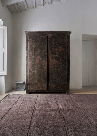Bruin Steppe-vloerkleed bij een houten kast.