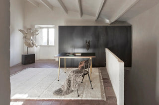 Wit Steppe-vloerkleed met beige randen bij een tafel en stoel op een vide.
