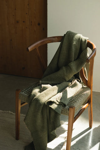 Khakigroene Legacy-plaid over een houten stoel.