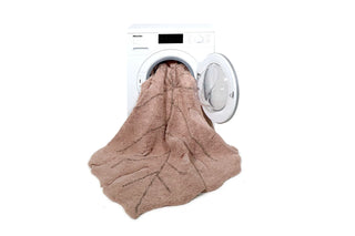 Rozebruin Monstera-kleed bij een geopende wasmachine.