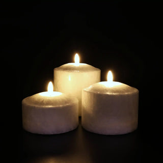 Witte brede Marble ledkaarsen in drie formaten, brandend tegen een donkere achtergrond van Mansion atmosphere