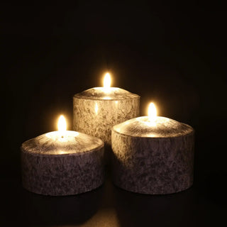 Zwarte brede Marble ledkaarsen in drie formaten, brandend tegen een donkere achtergrond van Mansion atmosphere