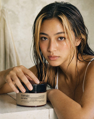 Model met hand op een pot Meraki Northern Dawn body butter