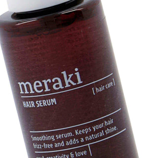 Close-up van het etiket op Meraki Hair Serum met tekst over glad, pluisvrij en glanzend haar
